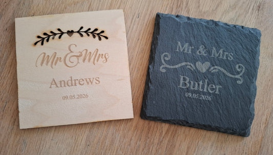 Wooden and slate coasters with engraved 'Mr & Mrs' names on a wooden surface